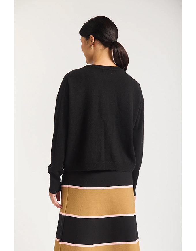 Person wearing a black sweater and a striped skirt with a white background