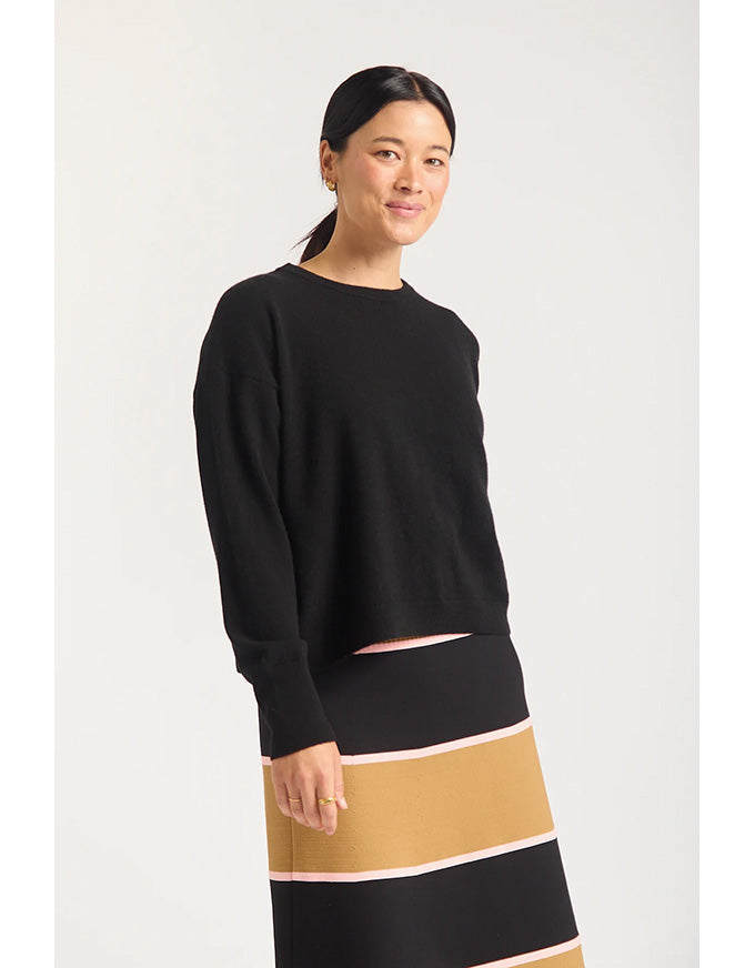 Woman wearing a black sweater and striped skirt on a white background