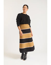Woman wearing a black sweater and striped skirt on a white background