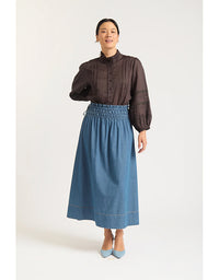 Woman wearing a brown blouse and blue denim skirt on a white background
