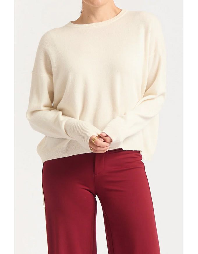 Person wearing a cream sweater and red pants on a white background