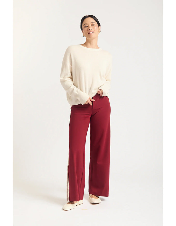Person wearing a cream sweater and red pants on a white background