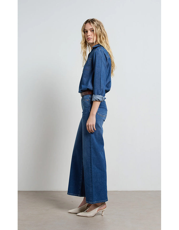 Woman wearing a blue denim outfit against a plain background