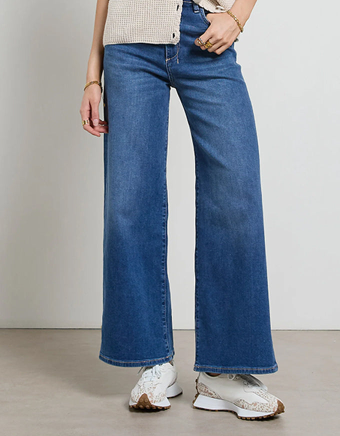 Person wearing blue wide-leg jeans with a neutral background