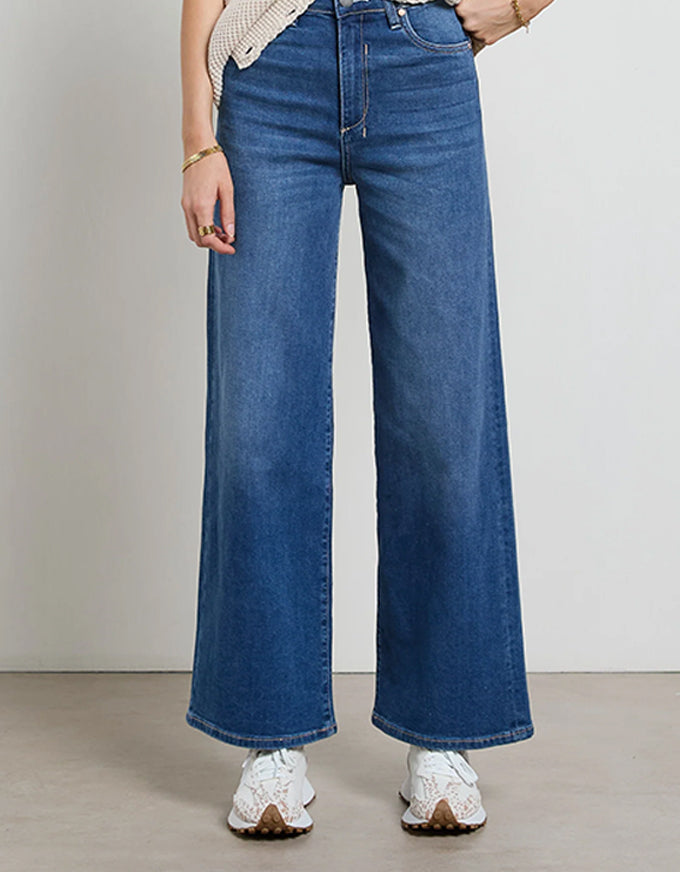 Person wearing blue wide-leg jeans on a plain background