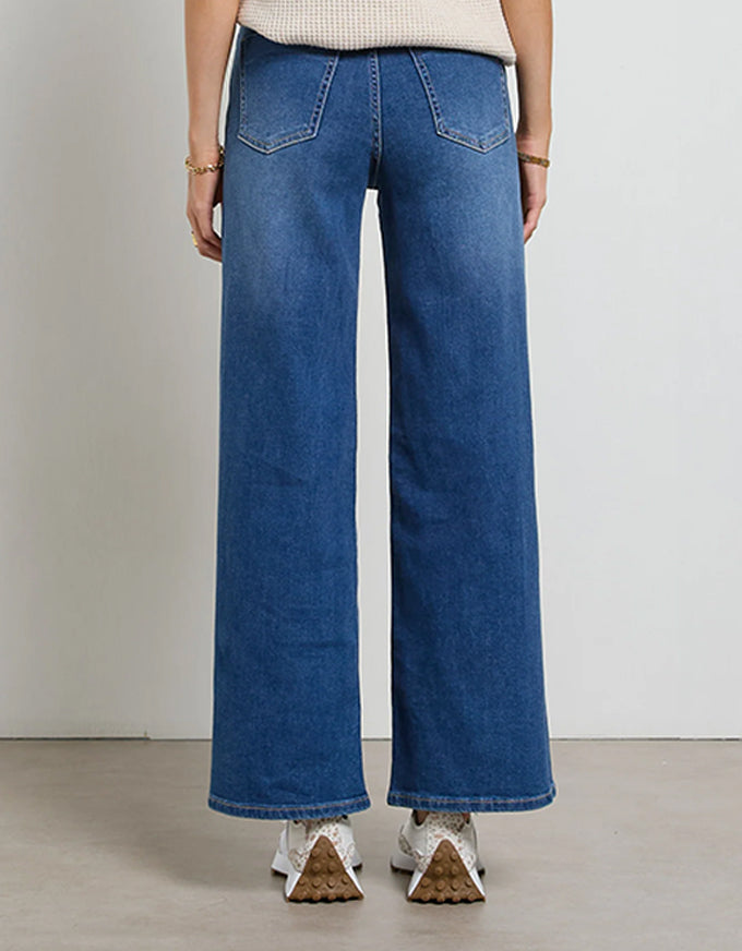 Person wearing blue wide-leg jeans on a plain background