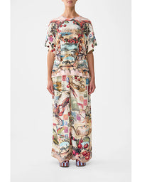 Person wearing a colorful patterned outfit on a white background. Notes From The Road Side Split Tee