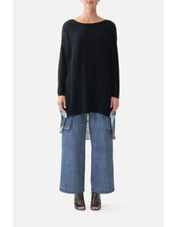 Person wearing a black sweater and blue jeans on a white background