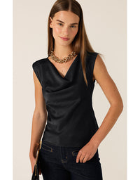 Woman wearing a black sleeveless top and jeans with a neutral background