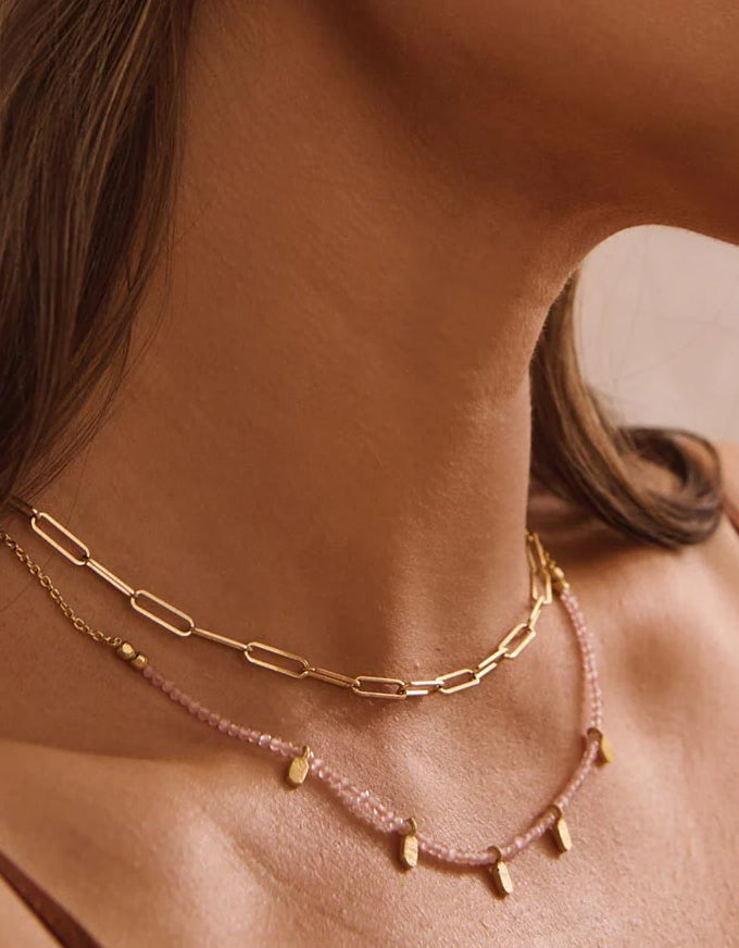 Close-up of a woman wearing two necklaces with a blurred background