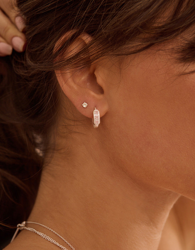 Close-up of a person wearing silver earrings with a blurred background
