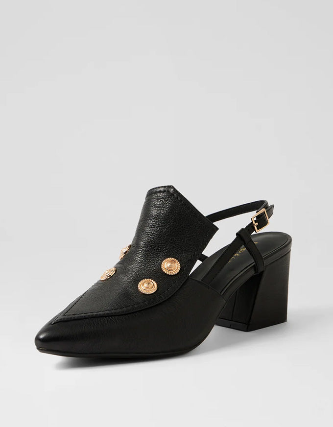 Black leather shoe with gold buttons on a light gray background