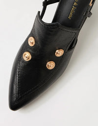 Black shoe with gold embellishments on a light gray background