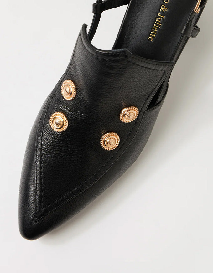 Black shoe with gold embellishments on a light gray background