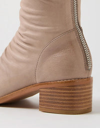 Close-up of a beige boot with a zipper on a white background