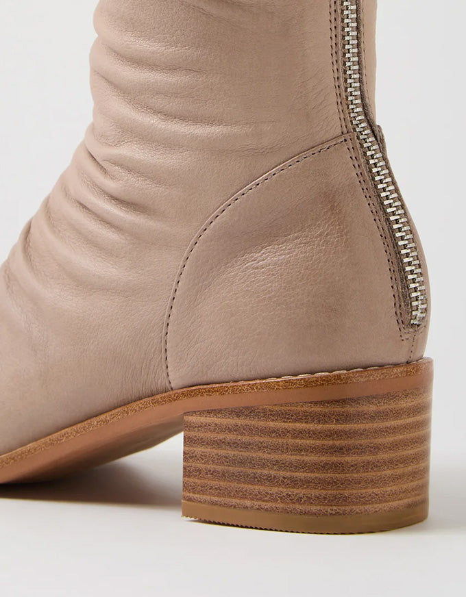 Close-up of a beige boot with a zipper on a white background