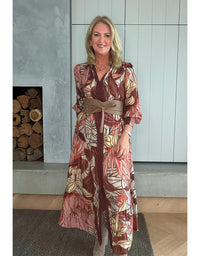 Woman wearing a patterned dress standing in a room with wooden logs.