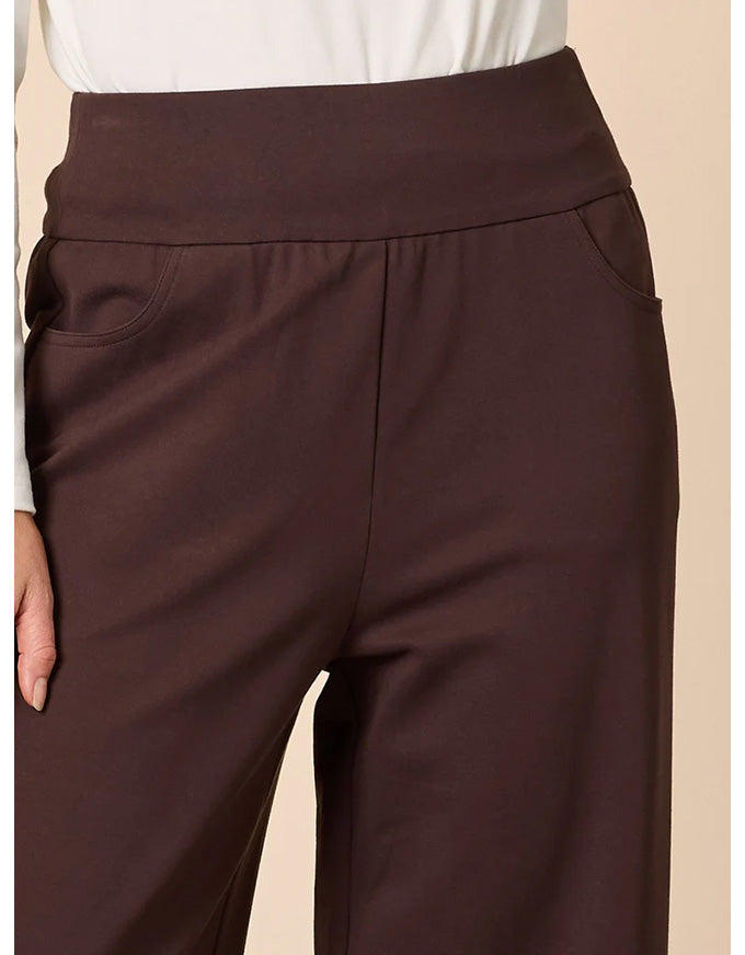 Brown pants worn with a white shirt on a beige background