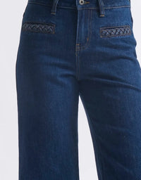 Blue jeans with braided details on pockets against a white background