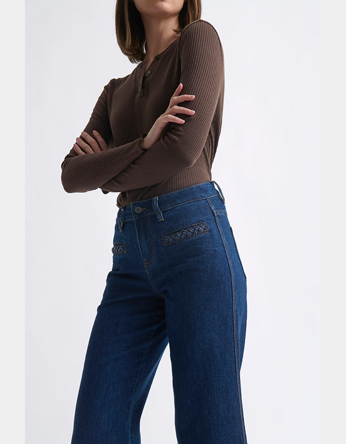 Person wearing a brown ribbed sweater and blue jeans on a white background