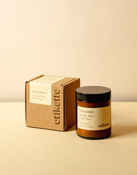 Candle and packaging with 'etikette' branding on a beige background