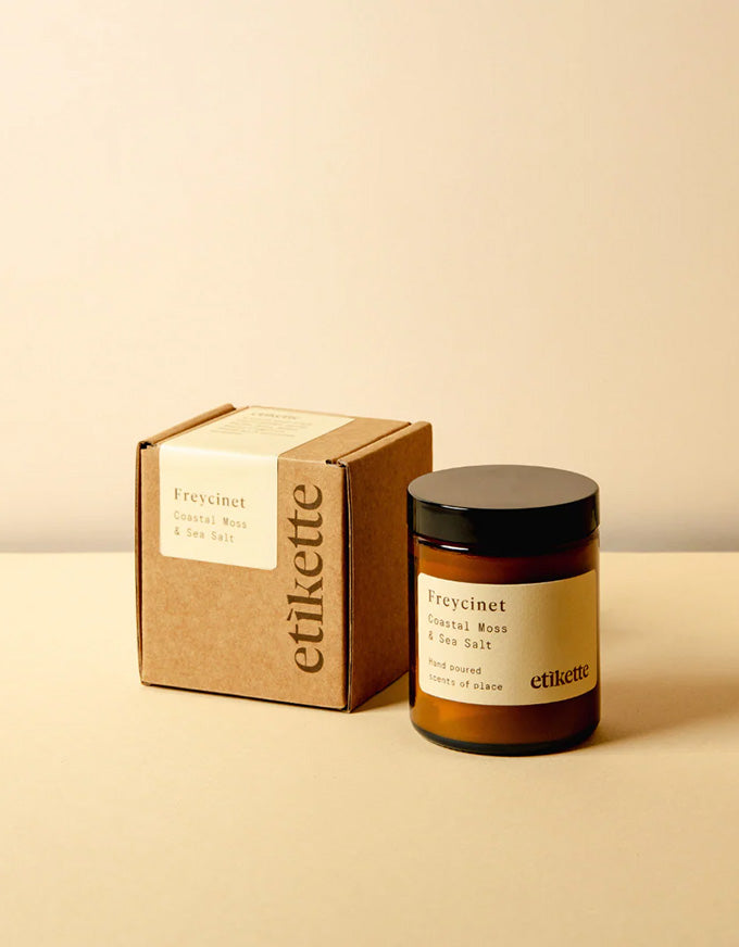 Candle and packaging with 'etikette' branding on a beige background