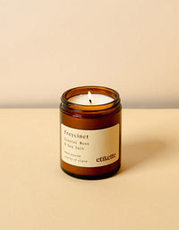 Candle in an amber jar with a label on a beige background