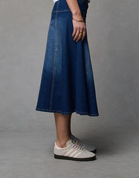 Person wearing a blue denim skirt with white sneakers on a gray background
