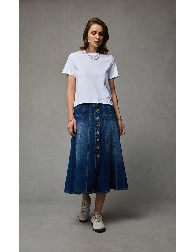 Woman wearing a white t-shirt and blue denim skirt on a gray background