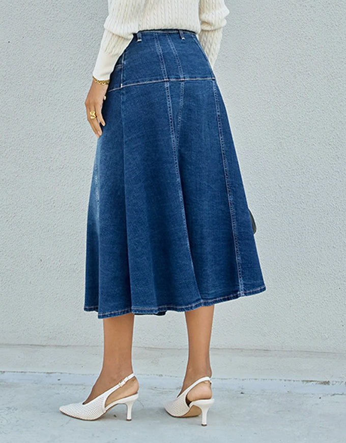 Person wearing a blue denim skirt with a plain background