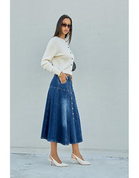 Woman wearing a white sweater and blue denim skirt against a light gray background