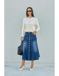 Woman wearing a white sweater and blue denim skirt against a light gray background