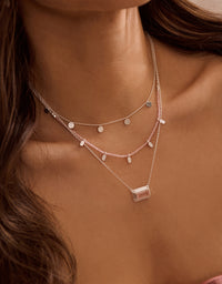 Close-up of a woman wearing multiple necklaces with a neutral background