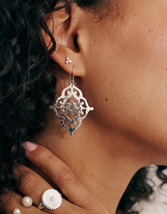 Close-up of a person wearing a silver earring with intricate design.