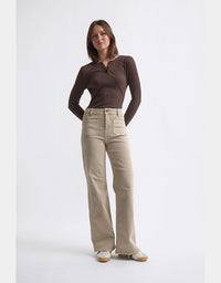 Woman wearing a brown top and beige pants on a white background