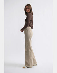 Woman wearing a brown sweater and beige flared pants on a white background