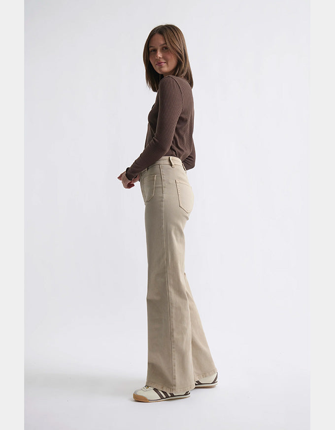 Woman wearing a brown sweater and beige flared pants on a white background