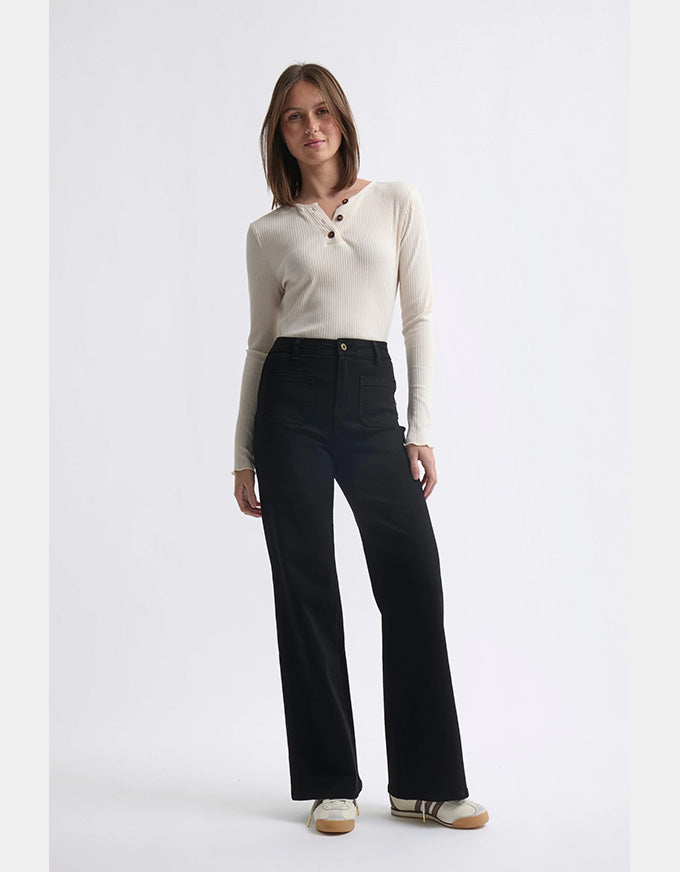Woman wearing a white long-sleeve shirt and black pants on a white background