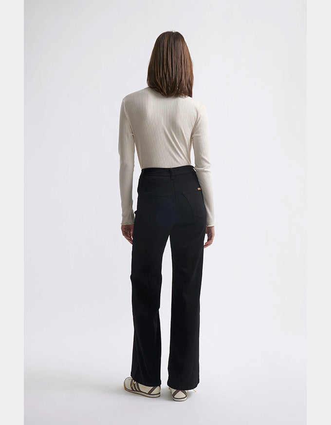 Person wearing a white long-sleeve top and black pants on a white background