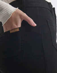 Close-up of black pants with a brand label on a white background