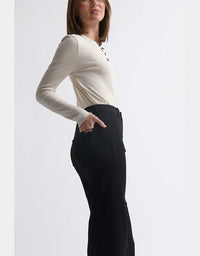 Person wearing a beige long-sleeve top and black pants on a white background