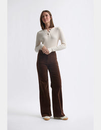 Woman wearing a white sweater and brown pants on a white background