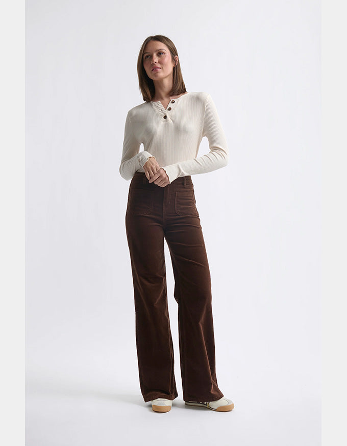Woman wearing a white sweater and brown pants on a white background