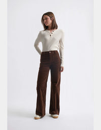 Woman wearing a white sweater and brown pants on a white background