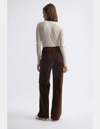 Person wearing a white long-sleeve top and brown pants on a white background