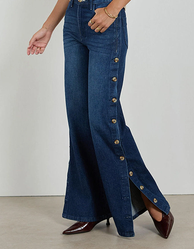 Blue flared jeans with button details on a plain background