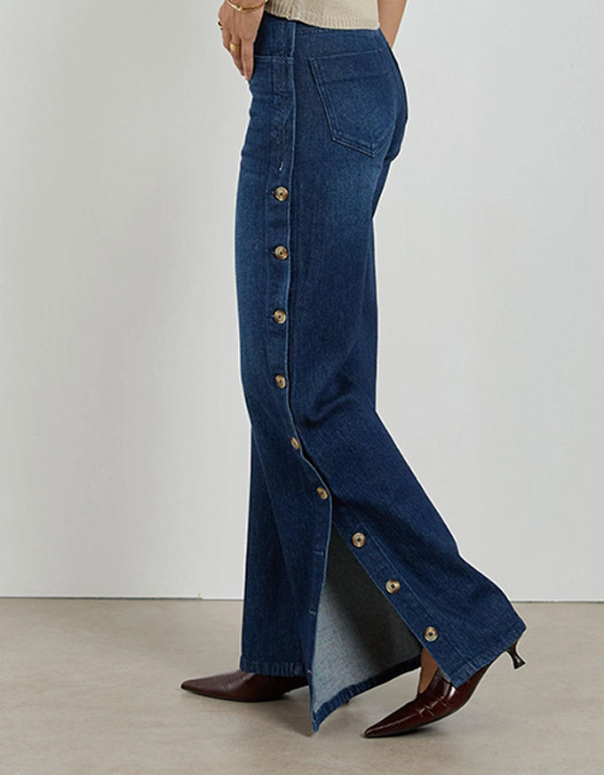 Blue denim pants with button details on a plain background