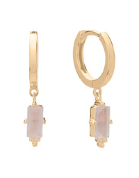 Gold hoop earrings with pink gemstones on a white background