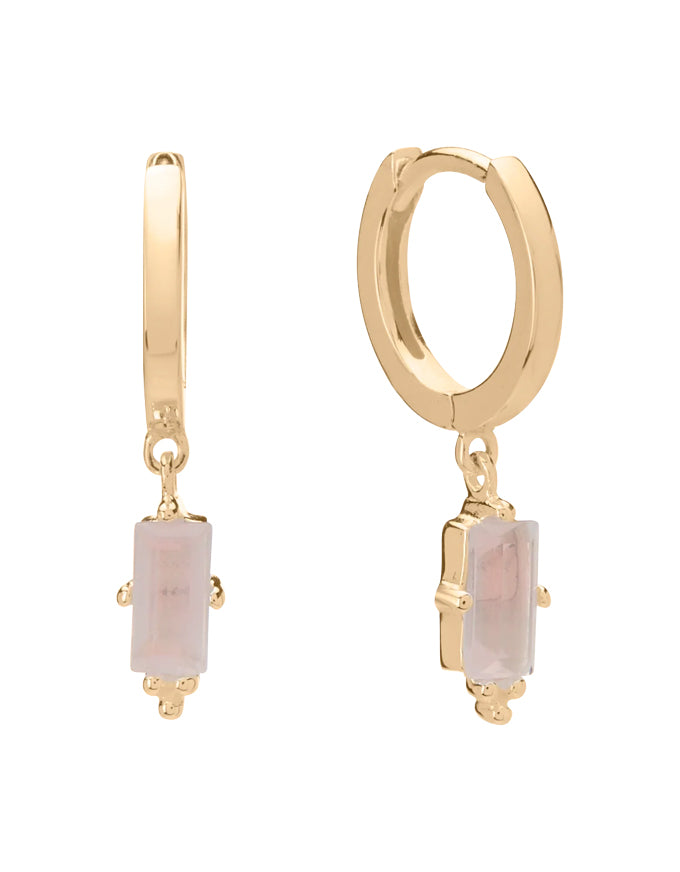 Gold hoop earrings with pink gemstones on a white background