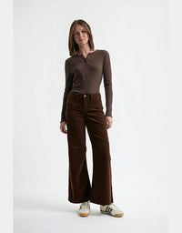 Woman wearing a brown long-sleeve top and brown wide-leg pants on a white background